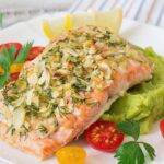 Delicious stuffed salmon with herb and cheese filling on a white plate garnished with lemon and herbs