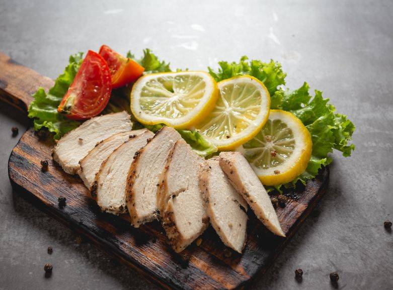 Juicy smoked chicken breasts on a wooden cutting board with herbs and spices