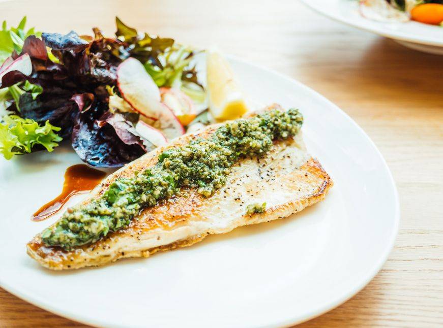 Freshly prepared Spinach Stuffed Salmon on a plate with lemon and herbs